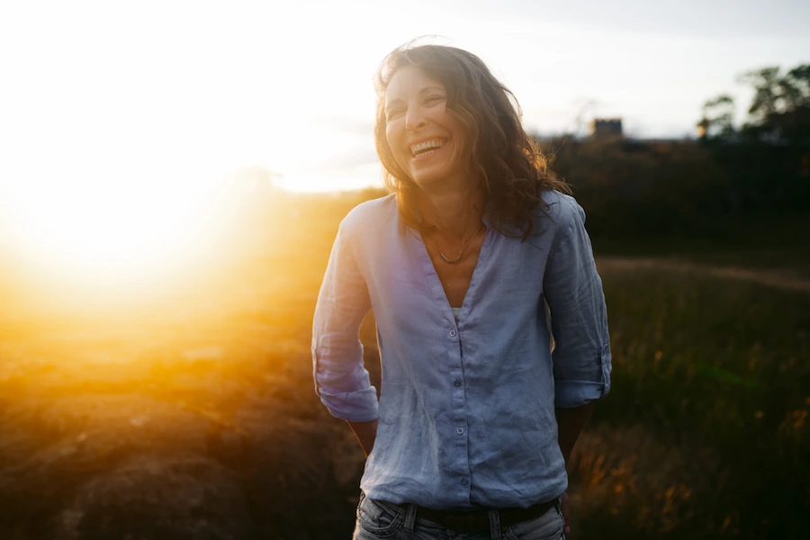 A happy woman protected by an FLFE high consciousness field standing in a field. 